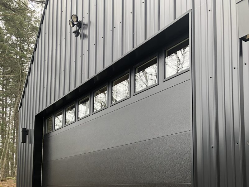 Black Steel Barn with Wide Garage Door and Overhead Lighting — Steel Buildings by Steel Bolt Construction